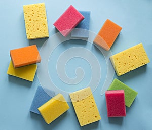 On a blue background lies a layout of different color sponges for cleaning the kitchen cleaning dishes