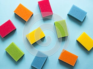 On a blue background lies a layout of different color sponges for cleaning the kitchen cleaning dishes flatlay