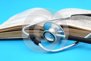 On a blue background lies a textbook book with a stethoscope. Medical education theme.