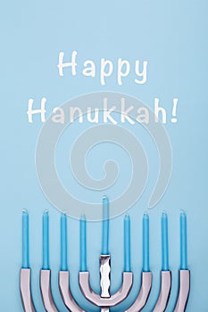 Blue background with menora and candles and Happy Hanukkah wording. Hanukkah and judaic holiday concept.