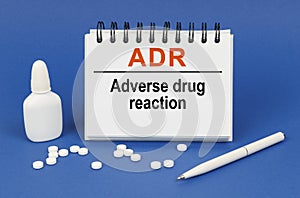 On a blue background, a pen, tablets and a notepad with the inscription - ADR Adverse drug reaction