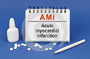 On a blue background, a pen, tablets and a notepad with the inscription - AMI Acute myocardial infarction