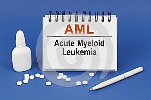 On a blue background, a pen, tablets and a notepad with the inscription - AML Acute Myeloid Leukemia
