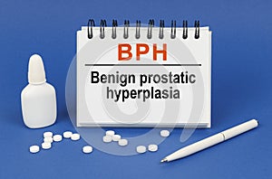 On a blue background, a pen, tablets and a notepad with the inscription - BPH Benign prostatic hyperplasia