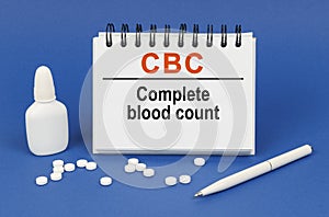 On a blue background, a pen, tablets and a notepad with the inscription - CBC Complete blood count