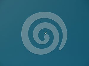 A blue background with a small white plane flying in the sky