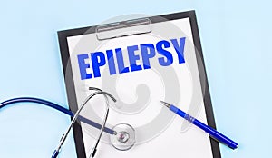 On a blue background, a stethoscope, a pen and a tablet with paper and the text EPILEPSY. Medical concept