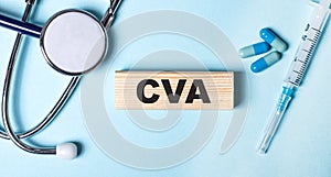 On a blue background, a stethoscope, a syringe and pills and a wooden block with the word CVA. Medical concept