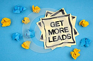 On a blue background, there are pieces of paper and a sticker with the inscription - GET MORE LEADS