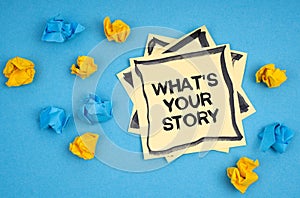 On a blue background, there are pieces of paper and a sticker with the inscription - WHAT S YOUR STORY