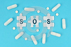 On a blue background, there are pills and puzzles with the inscription - SOS