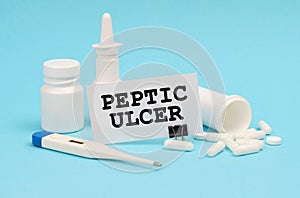 On a blue background, a thermometer, pills and a business card with the inscription - Peptic ulcer