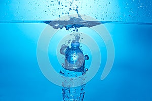 Blue background with water bottle falling in and multiplle drops and splashed. Water bubbles texture