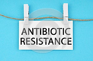 On a blue background, a white plaque hangs on a rope with the inscription - ANTIBIOTIC RESISTANCE