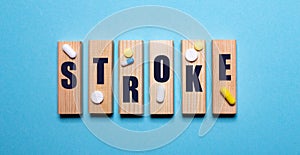 On a blue background, wooden blocks with the word STROKE and pills. Medical concept