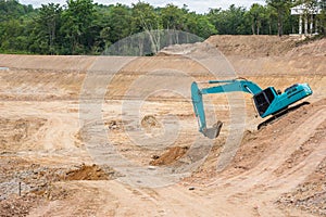 Blue backhoe excavating soil and sand