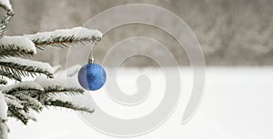 Blue ball, Christmas tree toy hanging on a Christmas tree in a snowy winter forest