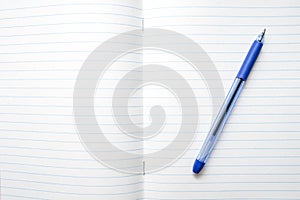 A blue ball pen lying on a blank lined school notebook sheet , paper with copy space