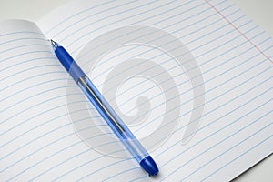 A blue ball pen lying on a blank lined school notebook sheet , paper with copy space