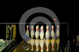 Blue ball rolling on a bowling alley lane with pins