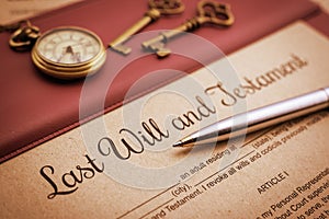 Blue ballpoint pen, antique pocket watch, two brass keys and a last will and testament on a vinyl desk pad. photo