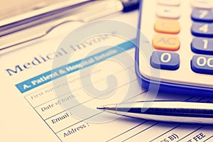 Blue ballpoint pen, a calculator and a medical invoice on a clipboard.