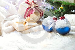 Blue balls with artificial snow, Christmas gift boxes and decorations on a white knitted blanket. New year, festive atmosphere, sp