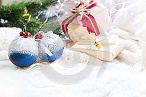 Blue balls with artificial snow, Christmas gift boxes and decorations on a white knitted blanket. New year, festive atmosphere, sp