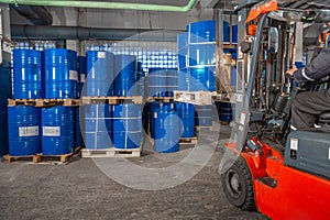 Blue barrels and red forklift in warehouse