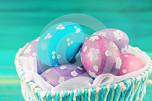 Blue Basket in the form of heart with Easter eggs. Blue wooden background. Happy easter.