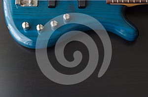 A blue bass guitar up a gainst a black wooden background