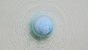 Blue bath bomb ball dissolves in water with white foam bubbles. Cosmetic product atural and skin care. Clear water with