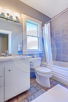 Blue bathroom with white cabinets with stone tiles and blue tiles.