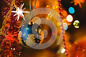 Blue bauble in Christmas tree surrounded by colourful lights