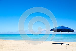 Blue beach umbrella parasol on the tropical beach. Vacation background