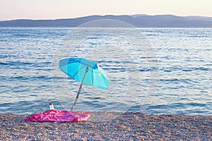 Blue beach umbrella on summer coast. Sea beach with sun umbrella is waiting for tourists on Sunset. Happy summer vacations concept