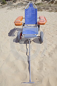 Blue beach wheelchair on sand ready to use