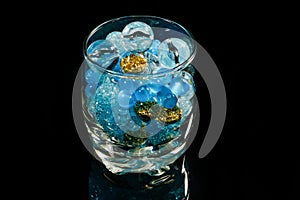 Blue beads balls in glass on black mirror background