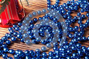 Blue beads with red christmas bell on old wood background