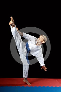 With a blue belt an athlete doing kick mawashi-geri on a black background