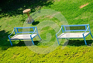 Blue benches and a side-table on grass at a park. Suitable as a background
