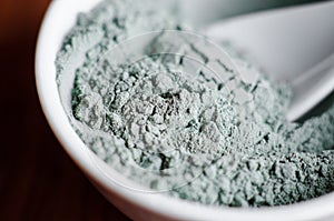 Blue bentonite clay powder in a bowl. Diy facial mask and body wrap recipe. Natural beauty treatment and spa. Clay texture closeup photo