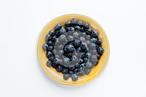 Blue berries in a yellow plate, top view