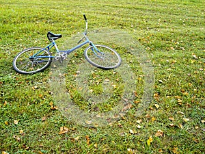Blue bicycle lie on summer-autumn feild on grass. Rest in the countryside