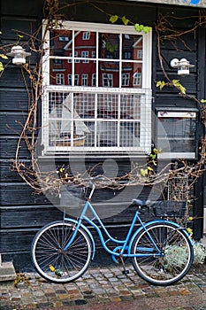 Blue bicycle under a window with sailboat and reflection in Copenhagen