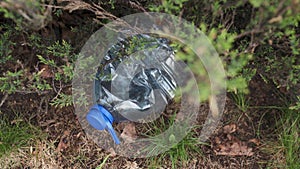 Blue big plastic bottle lying on the ground in tree in a park forest - Thrown out not recycled - Trash and pollution of