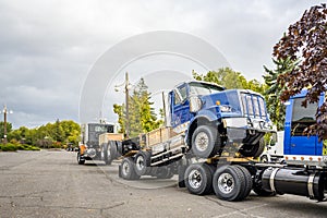 Blue big rig day cab semi truck towing another semi trucks coupled to each other with the fifth wheel saddle