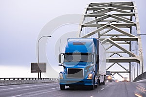 Blue big rig semi truck transporting semi trailer on arched Fremont bridge