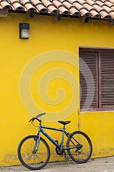 Blue bike leaning on a yellow wall of a traditional house