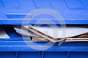 A blue bin for old paper and cardboard boxes